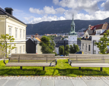 Two benches next to the sidewalk and a view of Nykirken Church in Bergen, Norway