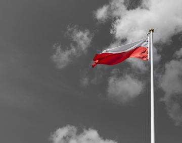 A red and white flag against a black and white sky