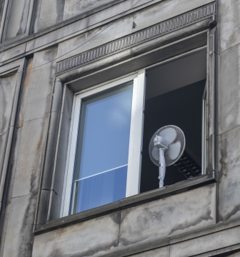 A fan in an open window during hot weather