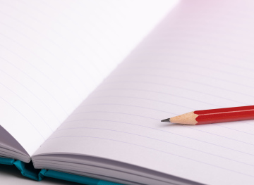 Open notebook and a red pencil