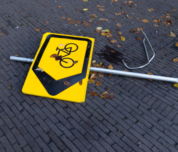 Overturned road sign, direction for bicycles.