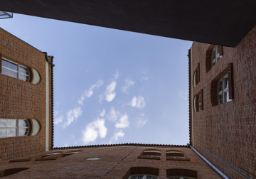 A narrow yard, brick buildings and a view of the sky