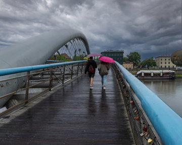 Bernatka footbridge in Krakow. People under umbrellas in the rain.