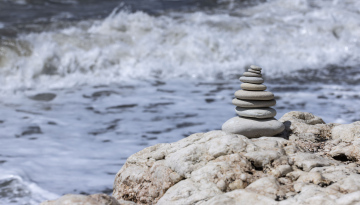 Stacked Pile of Stones on the beach and sea waves