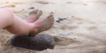 Feet on the beach stuck with sand