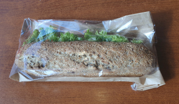 Sandwich with lettuce packed in paper and foil