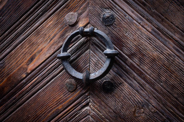 An antique door knocker on a wooden door
