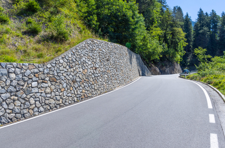 A winding road in a mountain area, a retaining wall of stones.