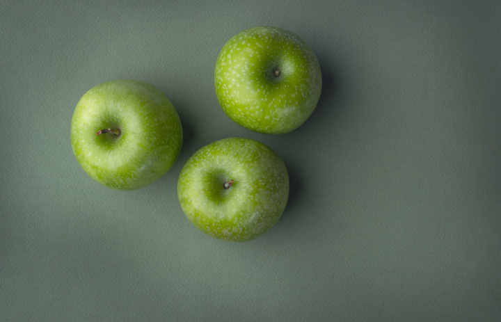 Three Green Apples On A Green Background