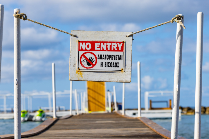 Closed entrance to the pier, closed beach, inscription in English and Greek, stock photo