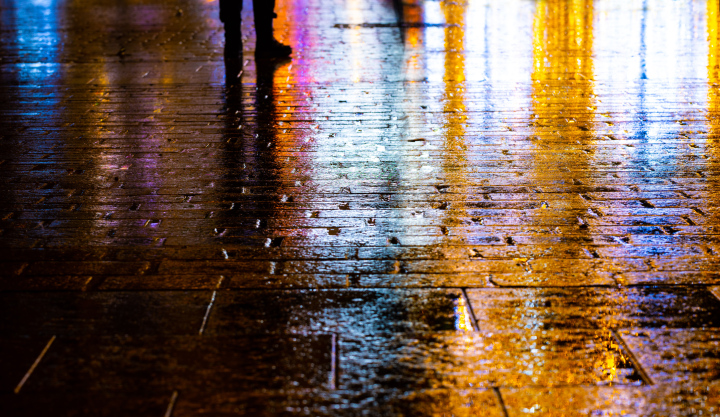 Evening rain in the square lit with colorful lights.