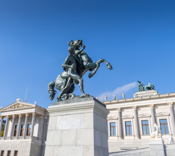 Figure with a horse sculpture in front of the Austrian parliament building.