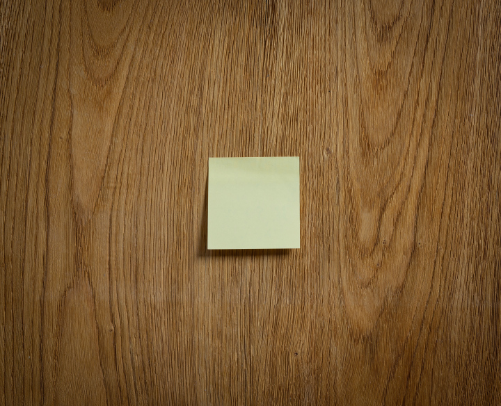 A yellow sticky note stuck to a wooden surface.